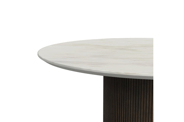 Primer plano de una mesa redonda con tablero de aspecto similar al mármol blanco y base oscura sobre un fondo blanco.