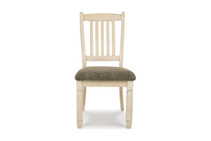 Una silla de comedor individual de madera con estructura pintada en color crema claro y asiento tapizado en gris texturizado, mostrada de frente sobre un fondo blanco liso.