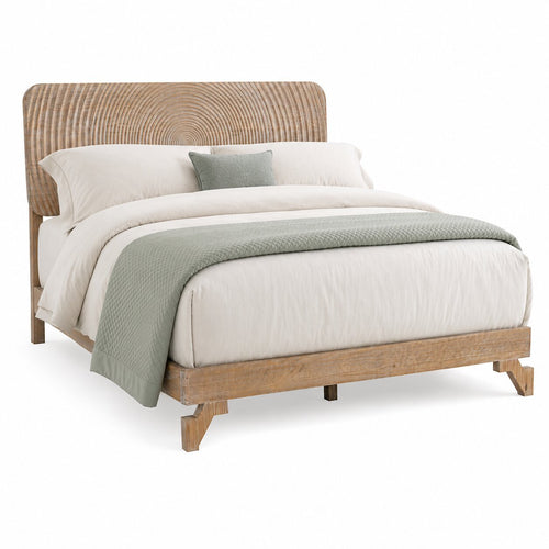 Una cama moderna tipo plataforma con estructura de madera natural clara y cabecero curvo de ratán tejido, decorada con ropa de cama blanca y una manta y almohada de color verde salvia sobre un fondo blanco.