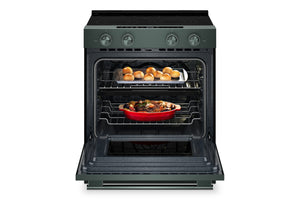 Un horno eléctrico independiente con exterior de color verde y puerta abierta, que deja ver dos rejillas con comida en su interior: una bandeja con pequeños panecillos dorados en la parte superior y una fuente roja para hornear en la parte inferior.