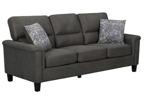 Un sofá tapizado en tela gris oscuro, con dos cojines decorativos con un estampado gris y blanco, sobre un fondo blanco liso.