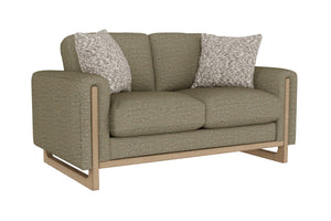 Loveseat de color verde con dos cojines decorativos sobre un fondo blanco. 