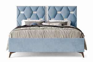 Cama tapizada en azul con cabecero estampado en forma de rombos sobre fondo blanco.