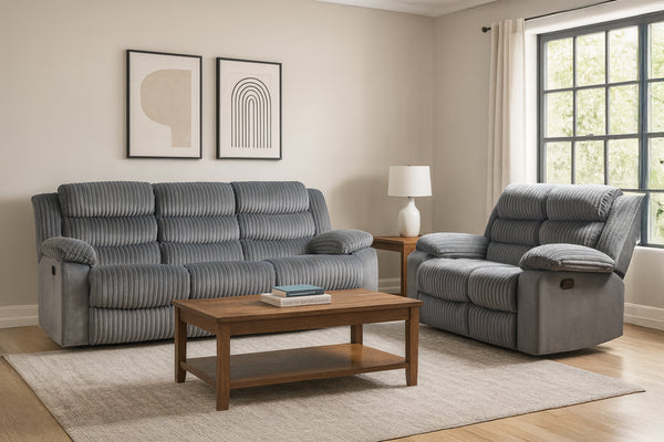 Sala moderna con sofá y sillón reclinable tapizados en tela gris acanalada, cojines acolchados y apoyabrazos amplios, acompañados de mesa de centro de madera, alfombra clara y grandes ventanas con luz natural.