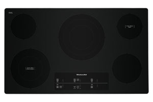 Un tope de cocción eléctrico KitchenAid negra con cuatro zonas de calentamiento circulares y un panel de control táctil en la parte inferior central, mostrada sobre un fondo blanco liso.