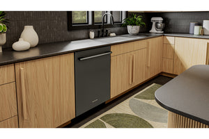 Un lavavajillas empotrado de color negro mate instalado bajo armarios de cocina de madera de roble claro con una encimera oscura y una alfombra estampada en verde y beige.