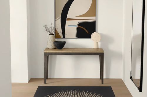 Mesa consola de madera con objetos decorativos contra una pared con arte abstracto.