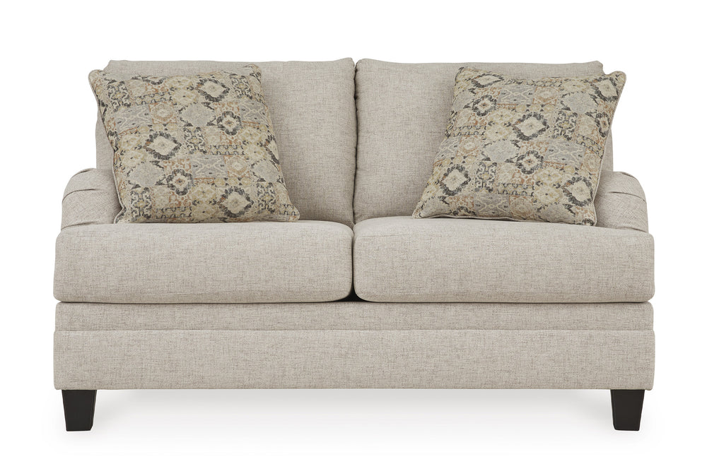 Loveseat beige con dos cojines decorativos y dos mesas de esquina a cada lado en un ambiente de sala. 