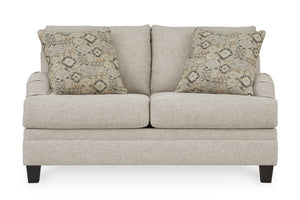 Loveseat beige con dos cojines decorativos sobre un fondo blanco. 