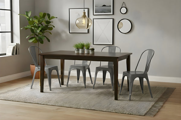Mesa rectangular de madera marrón oscuro con cuatro sillas grises en un ambiente de sala. 