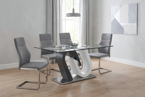 Juego de comedor moderno con mesa rectangular de cristal y base escultórica en tonos gris y blanco. Incluye cuatro sillas tapizadas en gris con detalles acolchados, en un espacio luminoso de estilo contemporáneo.