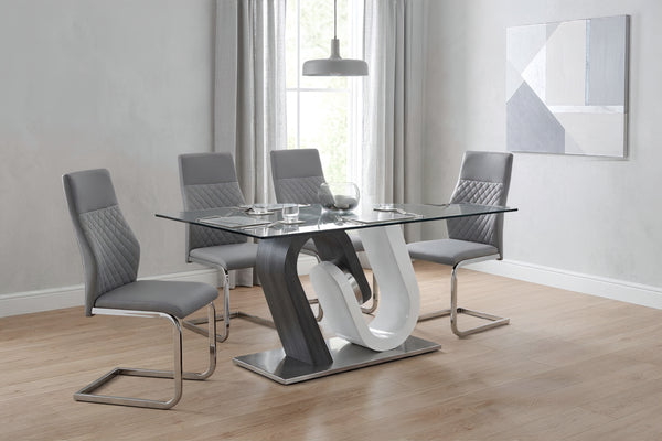 Juego de comedor moderno con mesa rectangular de cristal y base escultórica en tonos gris y blanco. Incluye cuatro sillas tapizadas en gris con detalles acolchados, en un espacio luminoso de estilo contemporáneo.