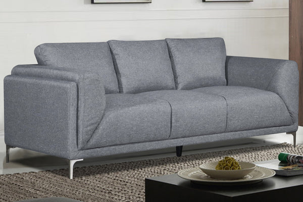 Sofá gris claro con patas metálicas en una sala con objetos decorativos. 