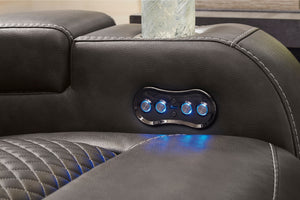 Panel de control con botones iluminados en un reclinable de cuero negro.
