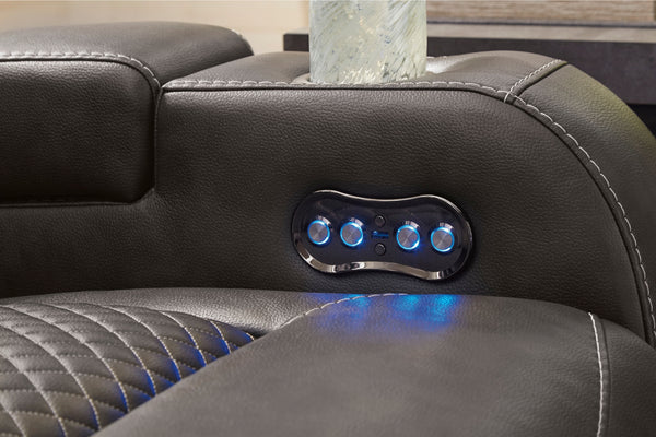 Panel de control con botones iluminados en un reclinable de cuero negro.