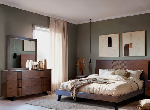 Un dormitorio moderno que cuenta con una estructura de cama de madera oscura con cabecero de listones y ropa de cama en tono beige, un gavetero de madera a juego con espejo y paredes de color verde oliva decoradas con arte abstracto.