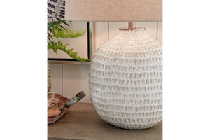 Lámpara de mesa texturizada sobre superficie de madera con fondo difuminado.