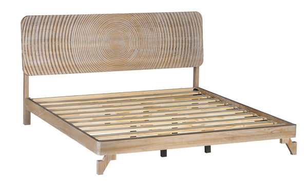 Estructura de cama tipo plataforma de madera natural clara con cabecero de ratán tejido con motivos circulares concéntricos, sobre un fondo blanco liso.