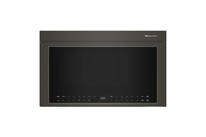 Horno microondas empotrable con acabado gris carbón oscuro, visto de frente sobre un fondo blanco liso. La marca «KitchenAid» es visible en la esquina superior derecha del marco de la puerta.