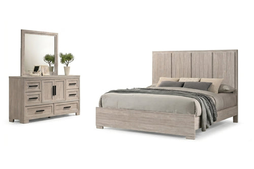 Un conjunto de muebles de dormitorio que incluye una cama con estructura de madera gris claro, cabecero alto con paneles y ropa de cama gris a juego, junto con una cómoda de madera gris claro a juego con un gran espejo.