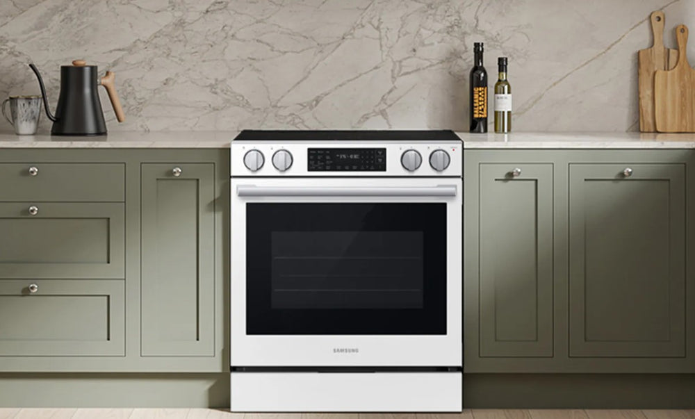 Samsung Estufa Eléctrica Bespoke de 30 pulgadas en acabado blanco, deslizable (slide-in), integrada entre gabinetes de cocina verdes y sobre encimera clara.