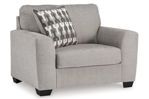 Silla de acento de color gris con cojín decorativo sobre un fondo blanco. 