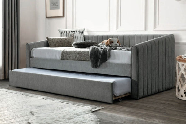 Sofá cama de color gris en una habitación con elementos decorativos. 