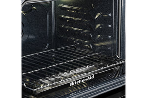Primer plano del interior de un horno KitchenAid negro, donde se aprecian la rejilla metálica y las bandejas del horno.