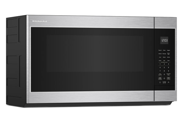 Un horno microondas KitchenAid para instalar sobre la encimera, con exterior de acero inoxidable y puerta de cristal negro, mostrado desde un ángulo de tres cuartos sobre un fondo blanco.