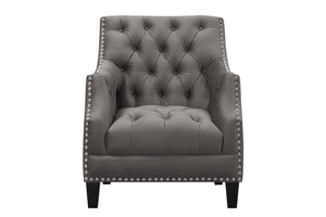 Sillón gris con respaldo capitoné y detalles de tachuelas sobre fondo blanco.