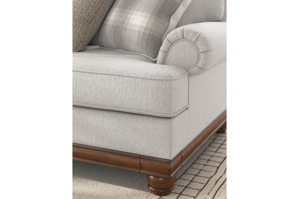 Sofá gris con patas de madera sobre fondo blanco.