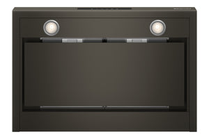 Vista inferior de campana extractora KitchenAid en acabado negro con dos luces LED encendidas, filtros metálicos de grasa visibles y panel frontal abatible, presentada sobre fondo blanco.