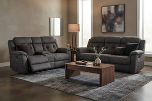 Juego de sala tapizado en gris oscuro con sofá y loveseat reclinable, uno con reposapiés extendido. Ambiente moderno con mesa de centro de madera, alfombra gris, cojines decorativos y lámpara de piso.
