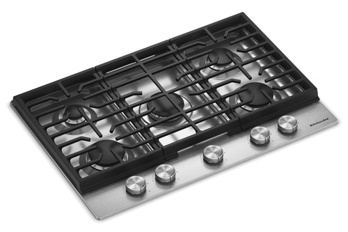 Un tope de cocina de gas de 5 quemadores con rejilla de hierro fundido negro y panel de control de acero inoxidable con cinco perillas plateadas, mostrada sobre un fondo blanco.