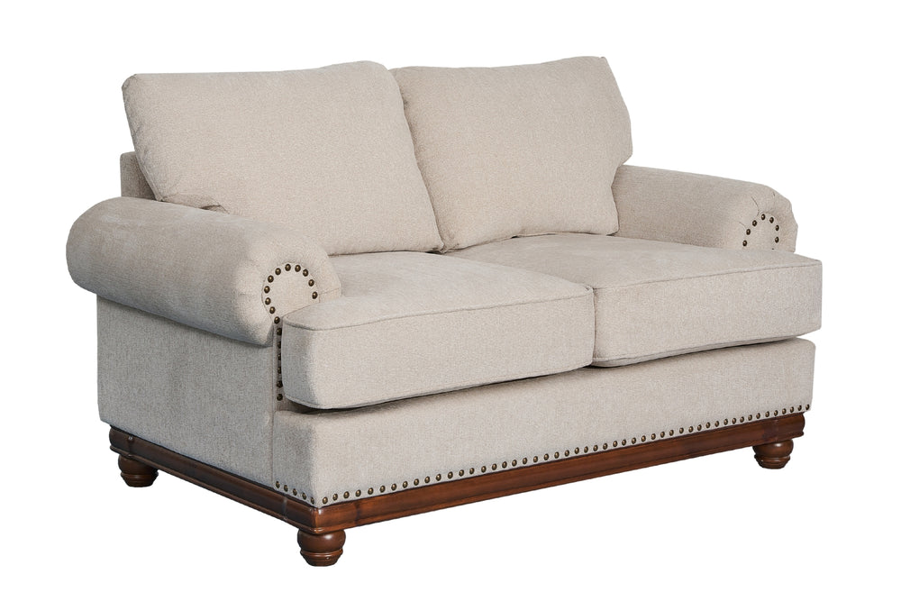 Loveseat clásico tapizado en tela beige clara, con cojines acolchados, apoyabrazos enrollados, detalles de tachuelas metálicas y base de madera oscura sobre fondo blanco.