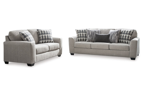 Sofá y loveseat de color gris claro con cojines sobre su fondo blanco. 