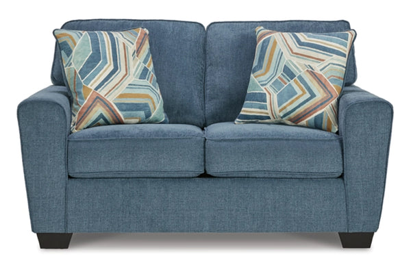 Loveseat de color azul con cojines sobre un fondo blanco. 