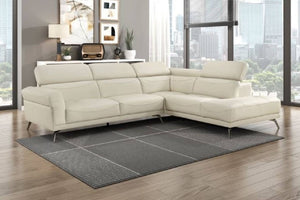 Seccional beige con patas acabadas en metal en una sala moderna con ventanas en el fondo. 