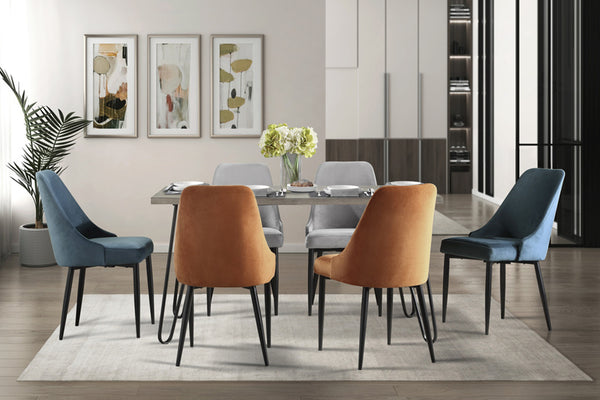 Mesa rectangular con patas acabadas en negro, tope de madera marrón, y seis sillas variadas en dos colores las cuales son azul, anaranjado y gris en una sala de comedor moderno. 
