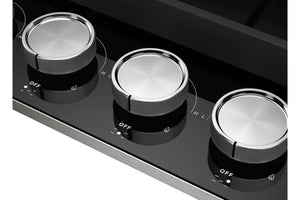 Primer plano del panel de control de una estufa negra con tres perillas plateadas metálicas etiquetadas como OFF, H y L.