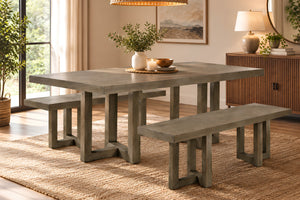 Una mesa de comedor rústica con acabado de hormigón gris y bancos a juego, situada en un comedor moderno y acogedor que cuenta con una alfombra de yute, un aparador y una iluminación cálida.
