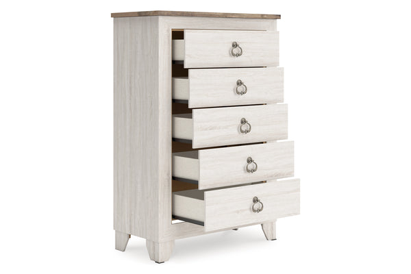 Un chest alto y estrecho de cinco gavetos con acabado de madera lavada en blanco, una tapa de madera café claro natural y tiradores de anillo de metal plateado, mostrado sobre un fondo blanco liso.
