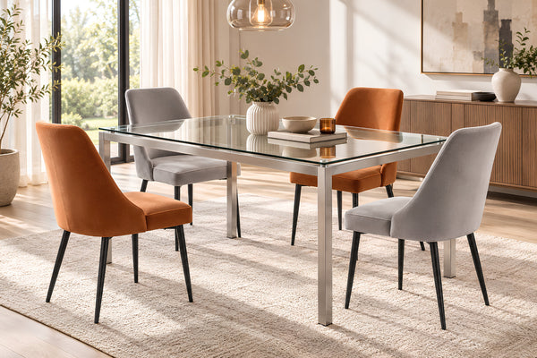 Un juego de comedor moderno que incluye una mesa rectangular con superficie de vidrio y estructura de metal cromado, acompañada de cuatro sillas tapizadas en naranja y gris claro, ambientado en un comedor luminoso y contemporáneo.