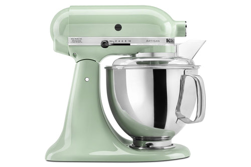 Una batidora de pie KitchenAid Artisan de color verde salvia claro, con un bol de acero inoxidable, tapa transparente y boquilla transparente para verter, mostrada sobre un fondo blanco liso.