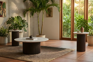 Sala de estar moderna con mesa de centro redonda y dos mesas redondas de esquinas con plantas en macetas y grandes ventanales.