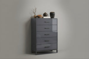 Chest de color gris oscuro con cinco gavetas y con objetos decorativos sobre un fondo gris. 