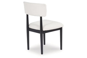 Una silla de comedor tapizada con asiento y respaldo de tela blanca, sostenida por una estructura de madera negra con cuatro patas, mostrada sobre un fondo blanco liso.