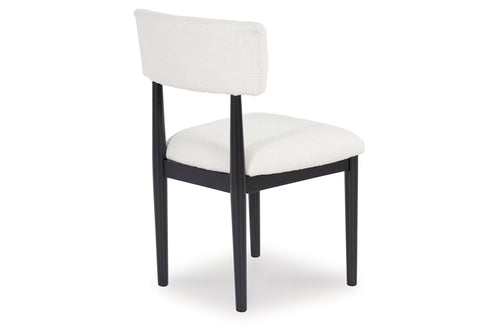 Una silla de comedor tapizada con asiento y respaldo de tela blanca, sostenida por una estructura de madera negra con cuatro patas, mostrada sobre un fondo blanco liso.