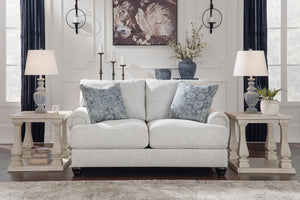 Loveseat blanco con cojines decorativos en un salón con mesas auxiliares y lámparas.