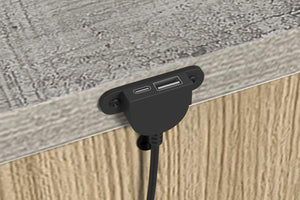 Puerto USB incrustado en una superficie de madera de una mesa de noche. 